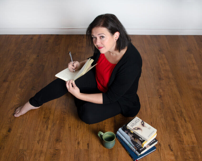 jenna morton sitting with books and coffee writing about pride of place parenting